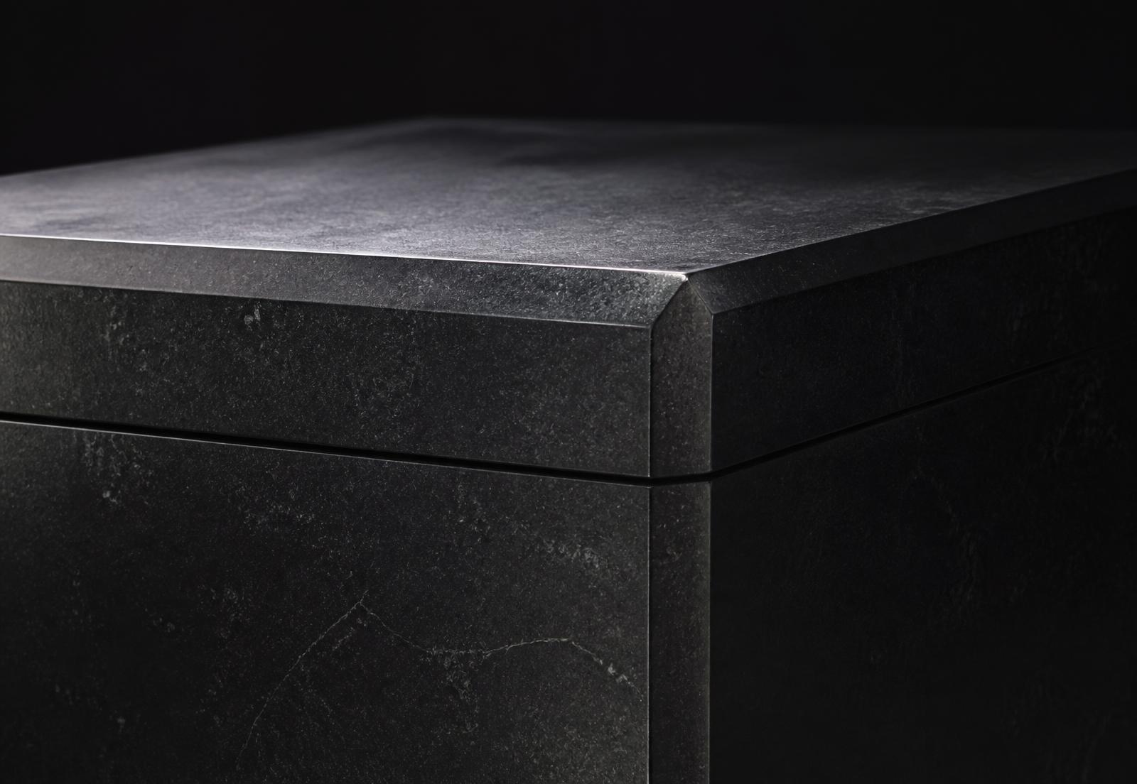 Honed black stone block with precision-cut seams under directional light